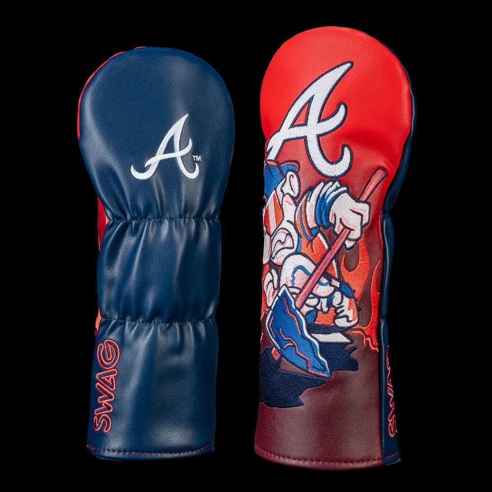 Back and front view of an Atlanta Braves fairway cover. The back features the embroidered Braves "A" logo on a navy panel. The front showcases a cartoon Braves mascot wearing mirrored sunglasses and headphones while gripping a tomahawk, set beneath an oversized Braves "A" against a fiery red background.