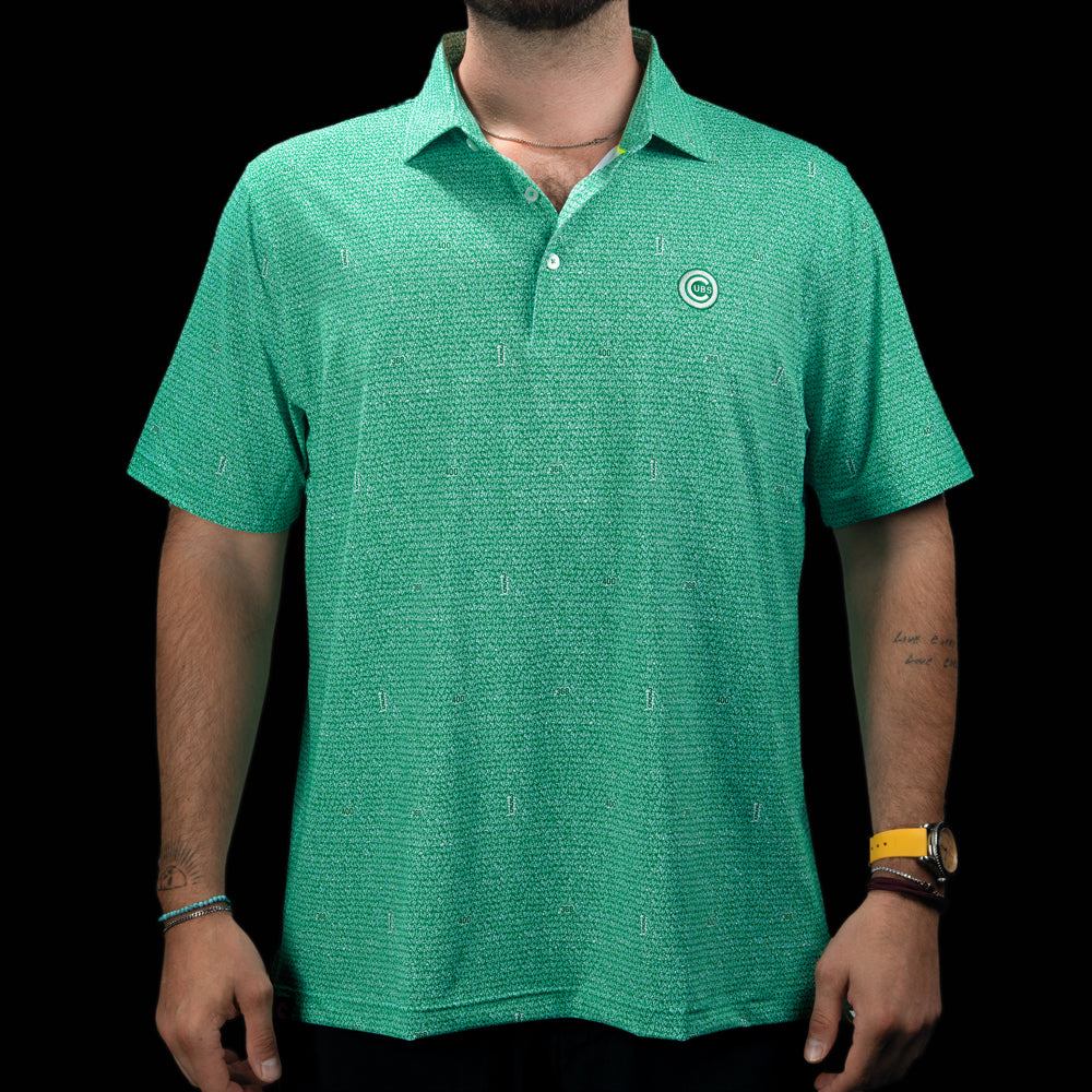 A man wearing a green short-sleeve polo shirt with a subtle textured pattern and a small circular logo on the left chest, photographed against a solid black background.