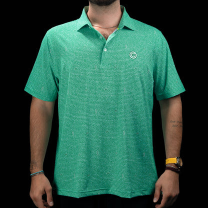 A man wearing a green short-sleeve polo shirt with a subtle textured pattern and a small circular logo on the left chest, photographed against a solid black background.