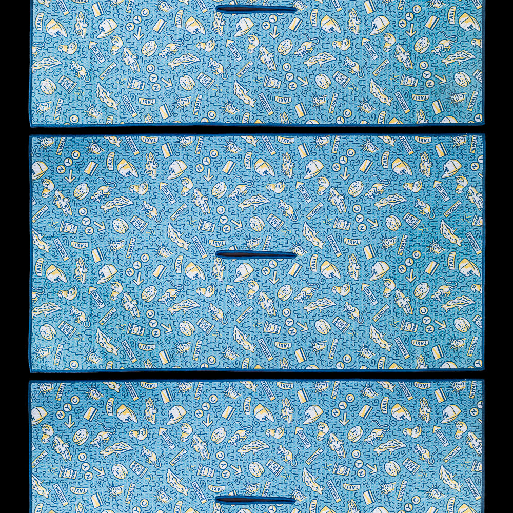 New York golf towel featuring an all over pattern of hand drawn New York inspired illustrations representing city landmarks, neighborhood culture, food, transit, and iconic local details in blue, cream, and gold.