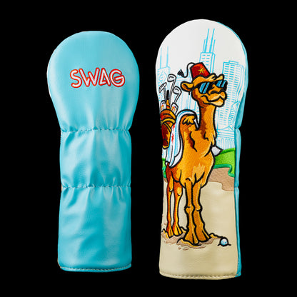 Over the Hump fairway wood cover featuring a sunglasses wearing camel carrying golf clubs on a sandy course with a blue city skyline.