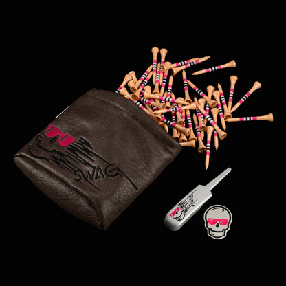 Brown vinyl SWAG golf tee pouch featuring embroidered skull logo with pink sunglasses, paired with matching metal divot repair tool and skull ball marker, displayed with striped wooden golf tees on a black background.