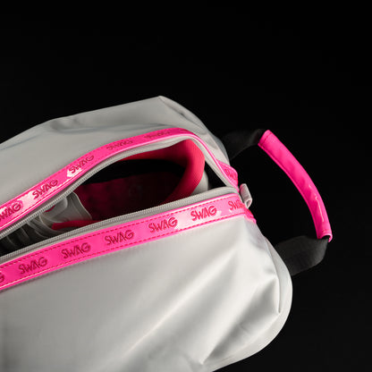 Angled detail shot of open SWAG Golf shoe bag with neon pink zipper accents, interior storage space, and pink carry handle.