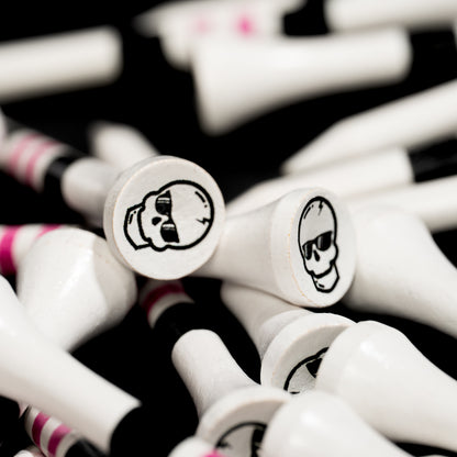 Close-up of white SWAG Golf tees featuring black skull logo graphics with pink and black striped detailing.