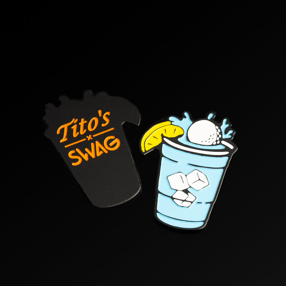 Tito's x SWAG ball marker featuring blue splash, floating ice, cocktail graphic, and a water hazard design. With Tito's X SWAG logo on the flip.