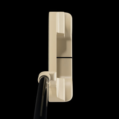 A close-up side view of a golf putter head in a warm cream color with a black shaft, set against a solid black background.
