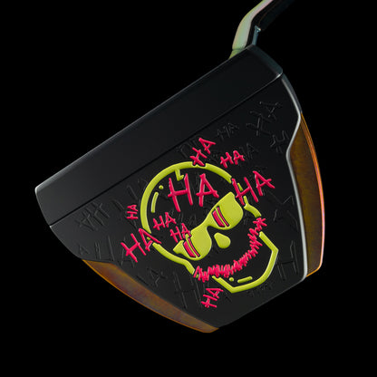 A black golf putter head featuring a bright yellow and red skull graphic with 'HA HA HA' text, shown against a solid black background.