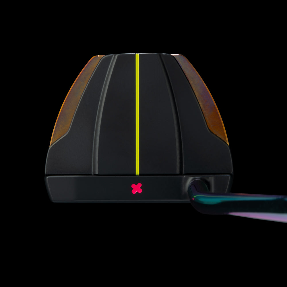 Close-up of a golf putter head on a black background, featuring a black face with a bright yellow center line, amber side panels, a small pink logo, and part of the iridescent green-purple shaft visible on the right.