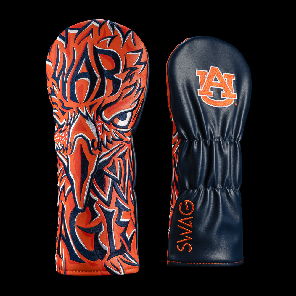 A pair of golf club headcovers on a solid black background. One cover features a bold orange and navy blue graphic design resembling a stylized Eagle face, while the other is dark navy blue with an orange 'AU' logo and the word 'SWAG' printed vertically in orange.