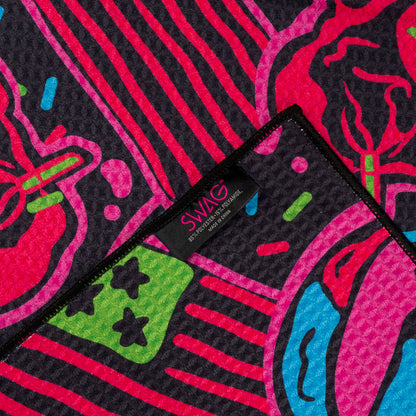 Close-up of the SWAGmas Burnt Cookie Towel showing neon red, blue, green, and pink cookie graphics with a SWAG Golf tag.