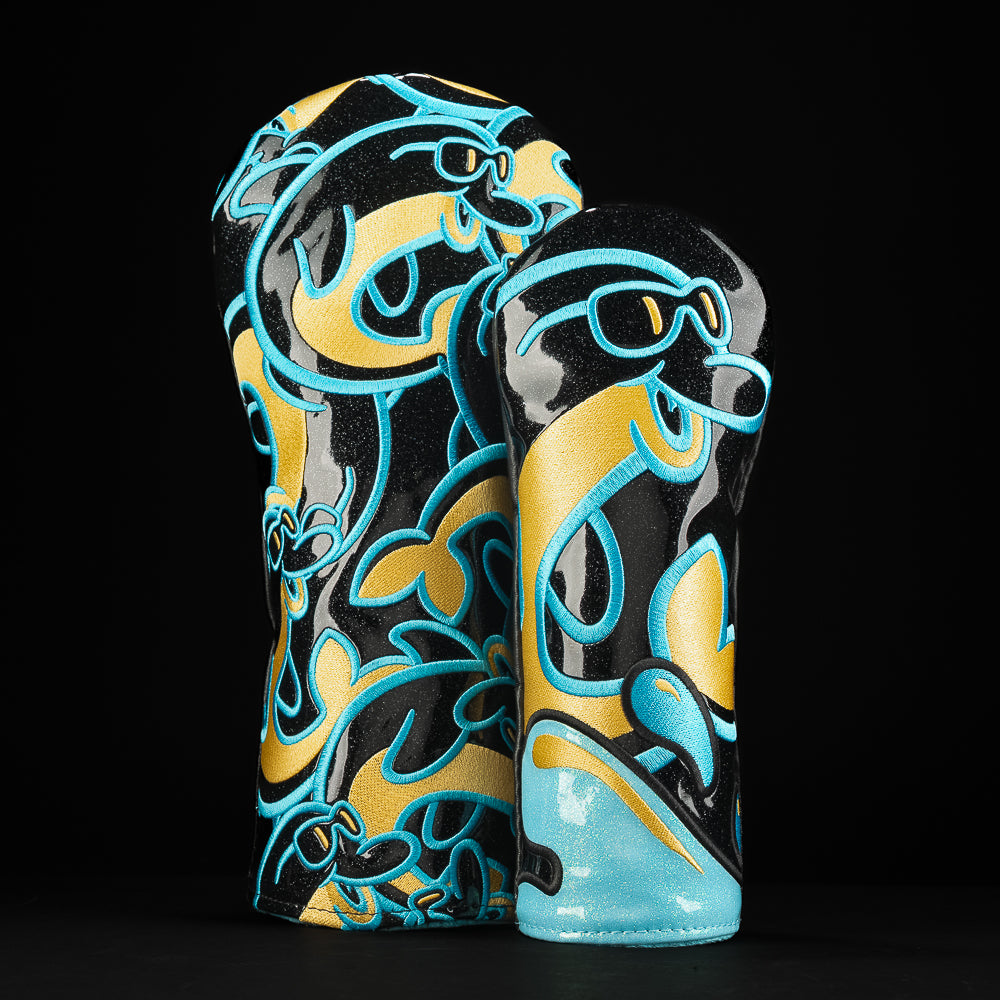 Matching aqua and yellow driver wood cover set with swirling dolphin character patterns and clean SWAG logos.