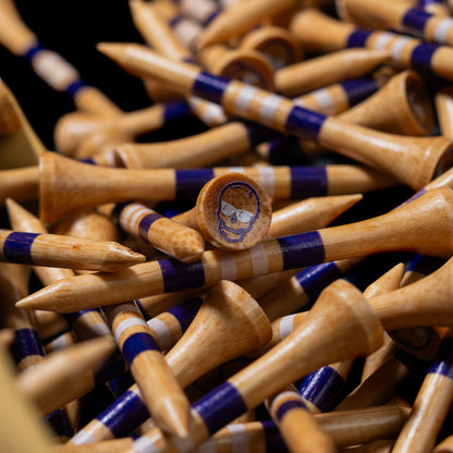 Close-up of the tan Taco Bell x SWAG Golf golf tees with purple bands and skull logo details.