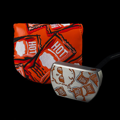 Taco Bell x SWAG Golf Hot Sauce BOSS 2.0 putter beside its orange Hot packet cover.