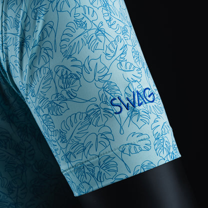 Swag x Peter Millar with an embroidered green Skull on a blue palm leaf print men's short sleeve golf polo shirt.