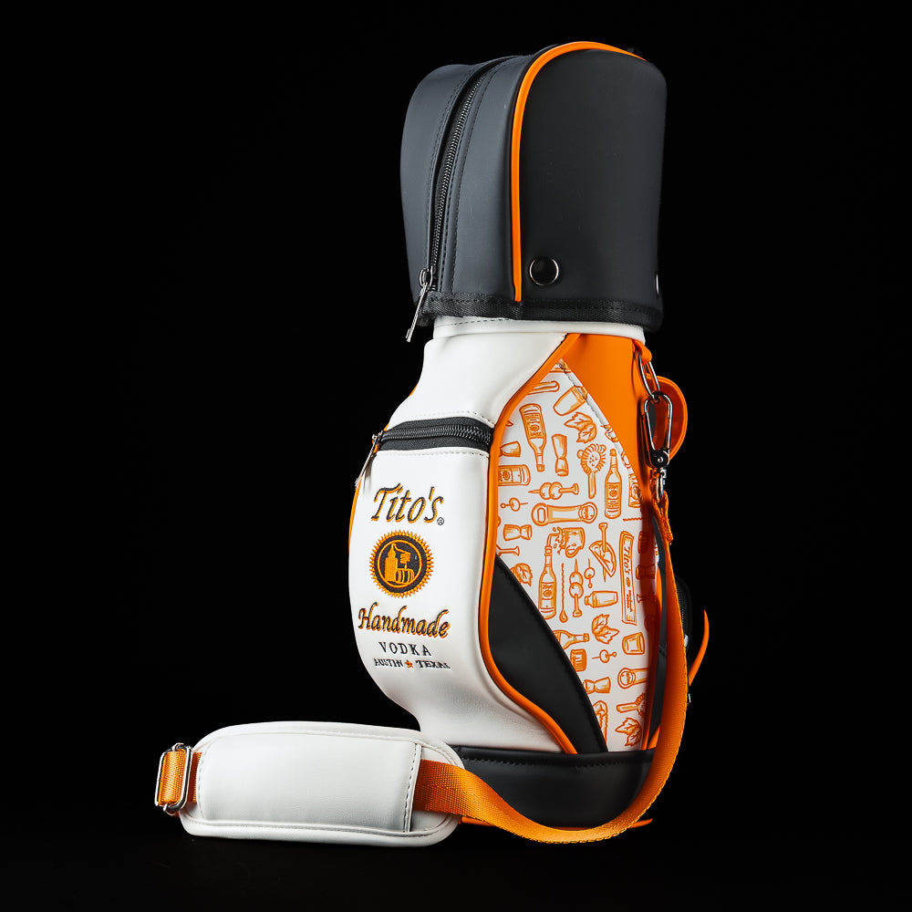 SWAG Golf Tito's Bottle Caddy featuring a white and orange design with Tito's Handmade Vodka branding, all over bottle icon pattern, shoulder strap, and black top cover.