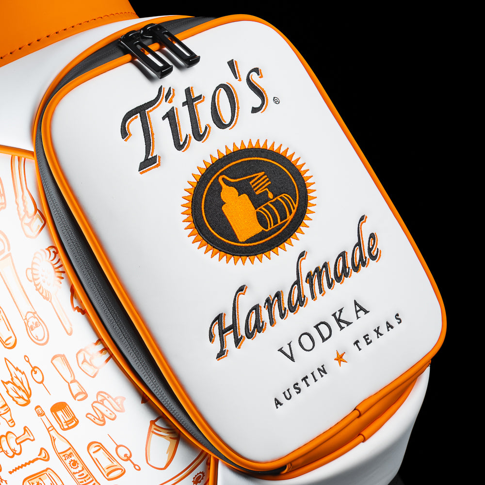 Close-up of the SWAG Golf Tito's Den Caddy Cooler zipper pocket featuring Tito's Handmade Vodka artwork and orange trim.