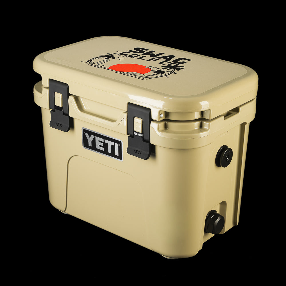 Angled view of the SWAG Golf x YETI tan hard cooler showcasing the custom lid artwork, front latches, and YETI logo.