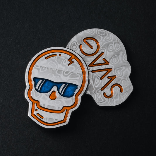 Damascus stainless steel Swag skull shaped golf ball marker accessory with orange and blue painted details.