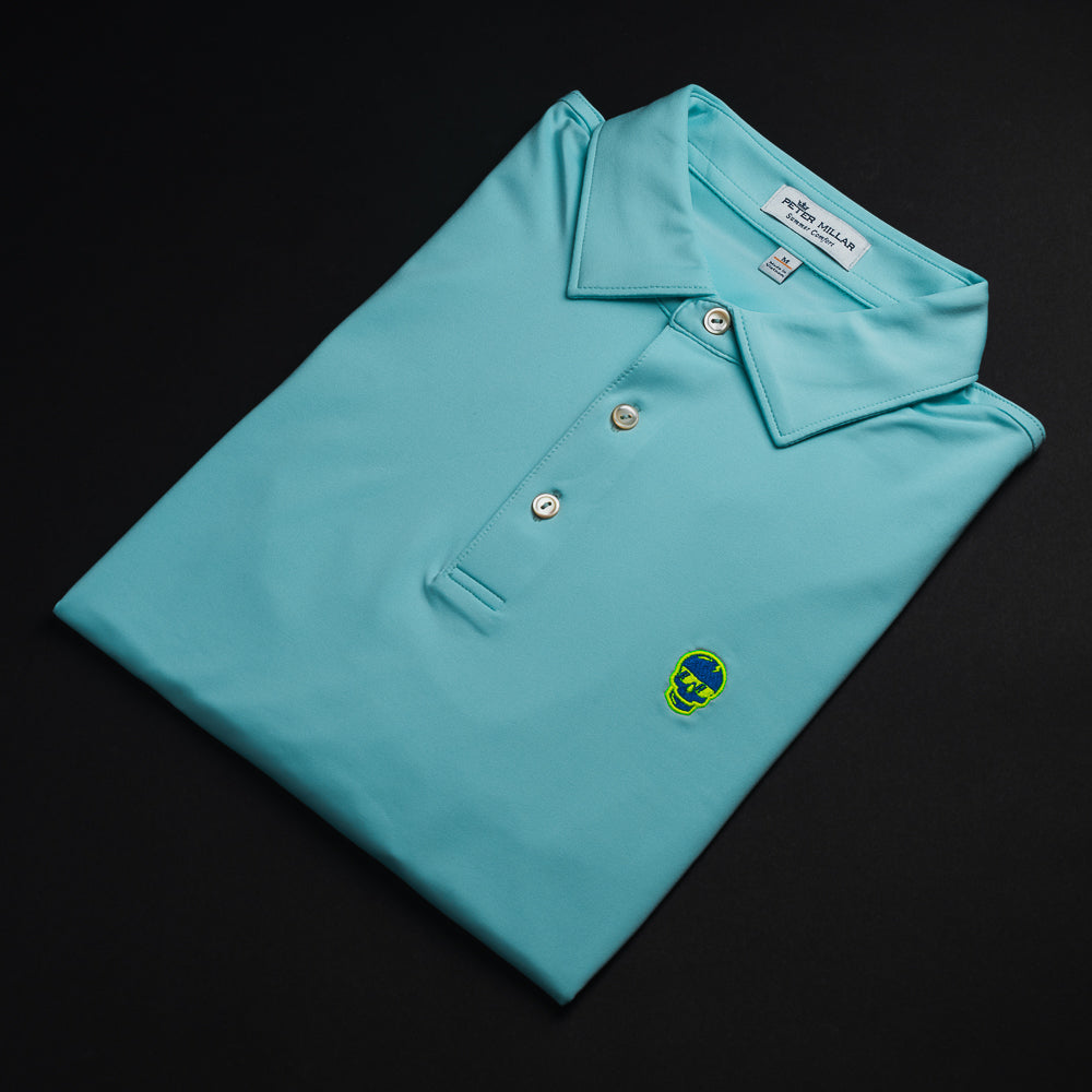 Swag x Peter Millar mint charged up men's short sleeve polo golf shirt with embroidered blue skull on left chest.